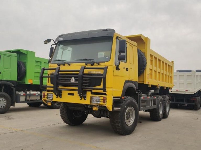 Camion à benne basculante HOWO 6X6 jaune garé sur un terrain, montrant sa calandre et ses phares robustes avec une grille de protection.