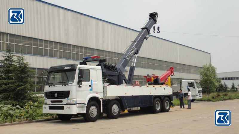 Le camion remorque HOWO 8X4 en opération sur une scène de sauvetage, avec son moteur WD615.69 et sa capacité de travail intensif, sa flèche étendue et ses multiples essieux pour assurer la stabilité.