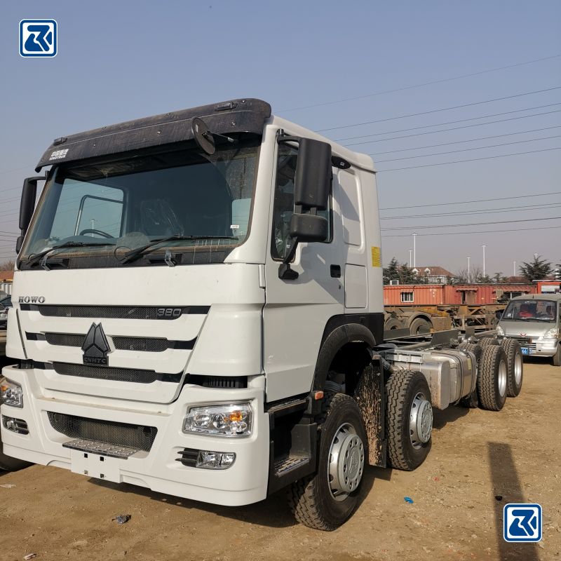 Vue latérale d'un camion cargo HOWO 6x6 blanc montrant le profil des pneus et la cabine du conducteur avec l'unité de climatisation sur le dessus.